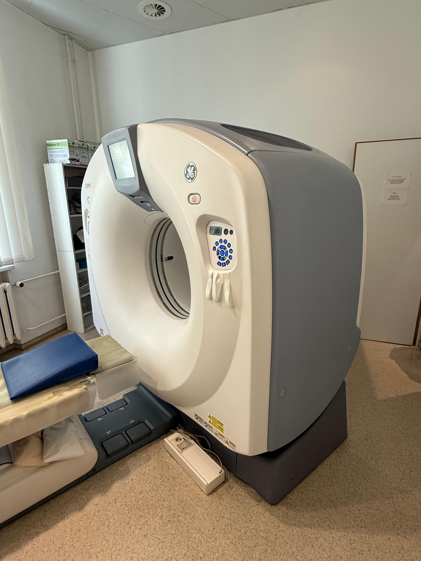 GE Optima CT520 16-slice CT scanner for sale — front three-quarter view of gantry and patient table inside clinical CT suite